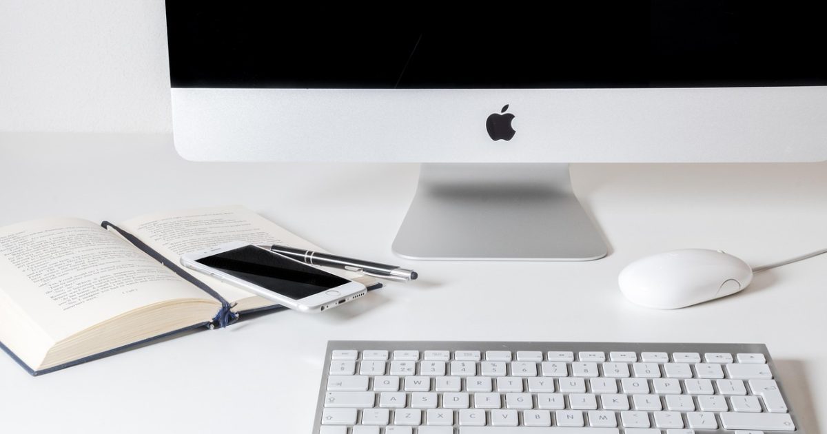 小游戏宝玩编辑部的深色桌面，两台显示器上并排打开小游戏类型目录与笔记窗口，靛蓝色的屏幕光落在键盘与摊开的纸质清单上，氛围安静专注